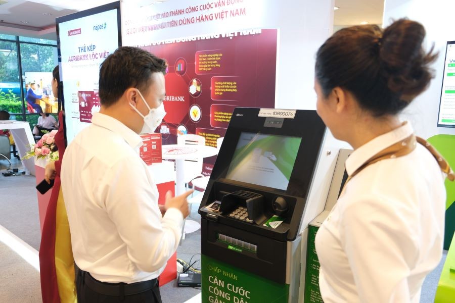 Cán bộ Vietcombank tư vấn khách hàng sử dụng dịch vụ ngân hàng số  (ảnh trên) và dịch vụ ATM (ảnh dưới) tại gian hàng trưng bày