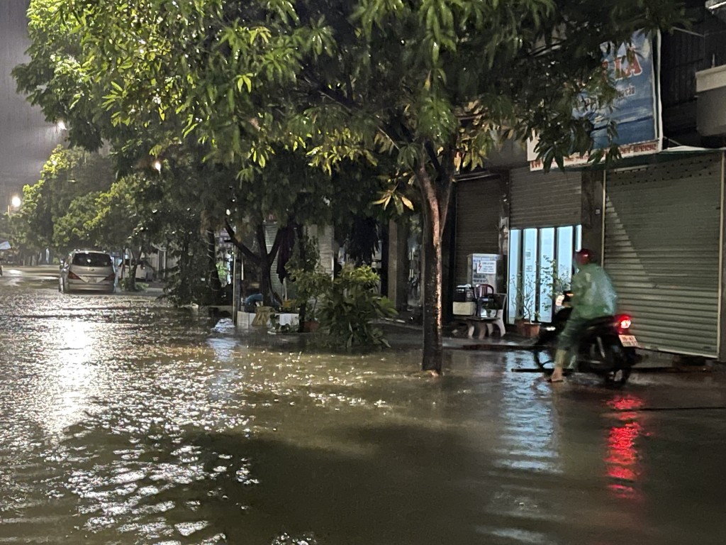 Người dân phải đi lên vỉa hè hoặc vào trú tạm tại nhà dân ven đường để đợi nước rút bớt mới dám đi qua.