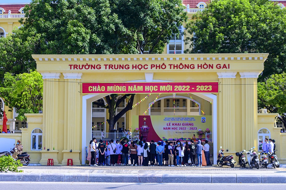 Phụ huynh học sinh đứng bên ngoài cổng trường để dõi theo con em mình tham dự ngày hội khai giảng năm học mới. 