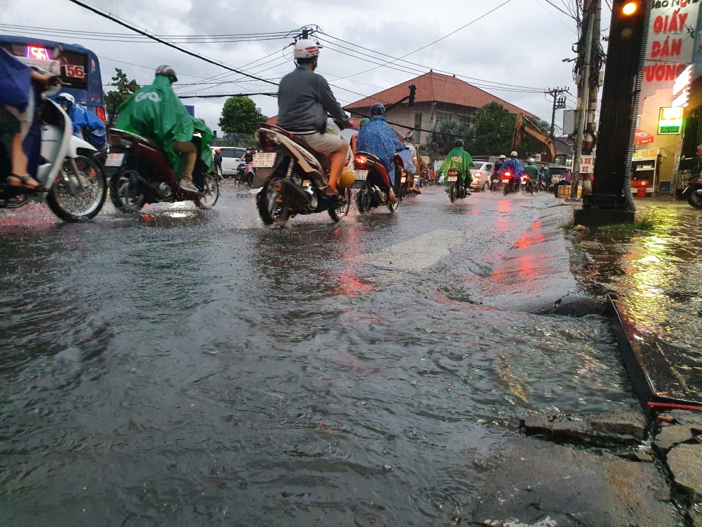 Cơn mưa không lớn nhưng nước từ dưới cống trào ngược lên mặt đường gây ngập và ô nhiễm. phía xa là lô cốt án ngữ ngay khu vực giao lộ Võ Văn Ngân - Đặng Văn Bi.