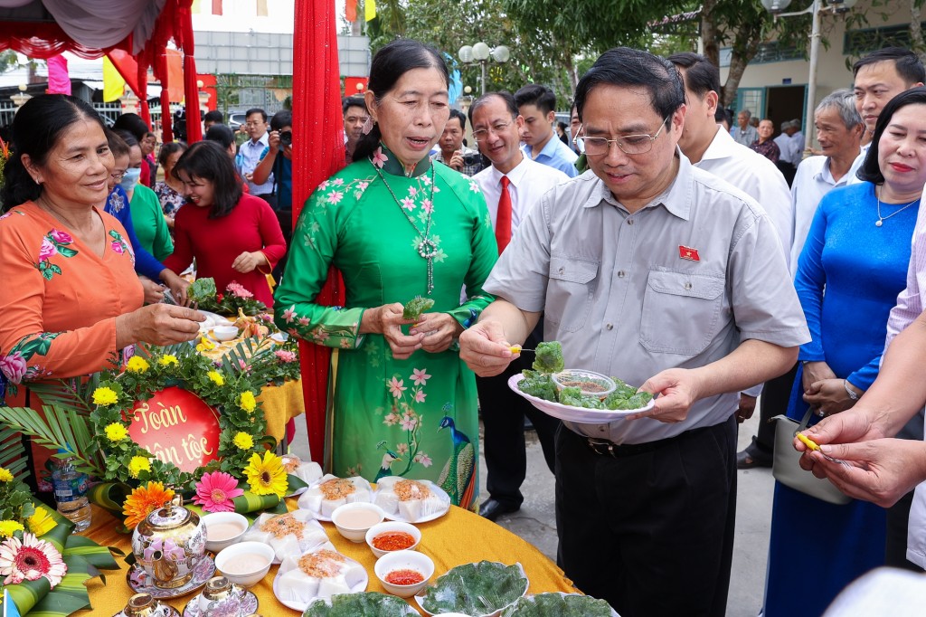 Thủ tướng nếm thử sản phẩm bánh truyền thống của người dân ấp Nhơn Thọ dự thi nhân ngày hội - Ảnh: VGP/Nhật Bắc