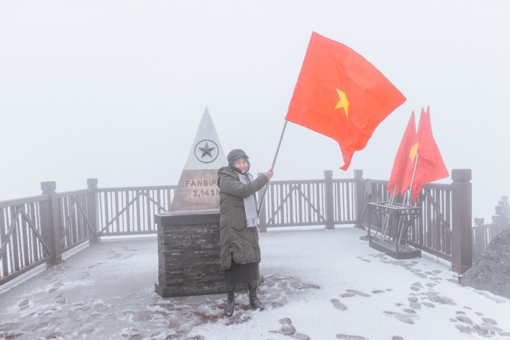 Bên chóp tháp Fansipan đánh dấu cột mốc 3143m, du khách hào hứng và tự hào phất cao cờ Tổ quốc đỏ rực trên nền tuyết trắng