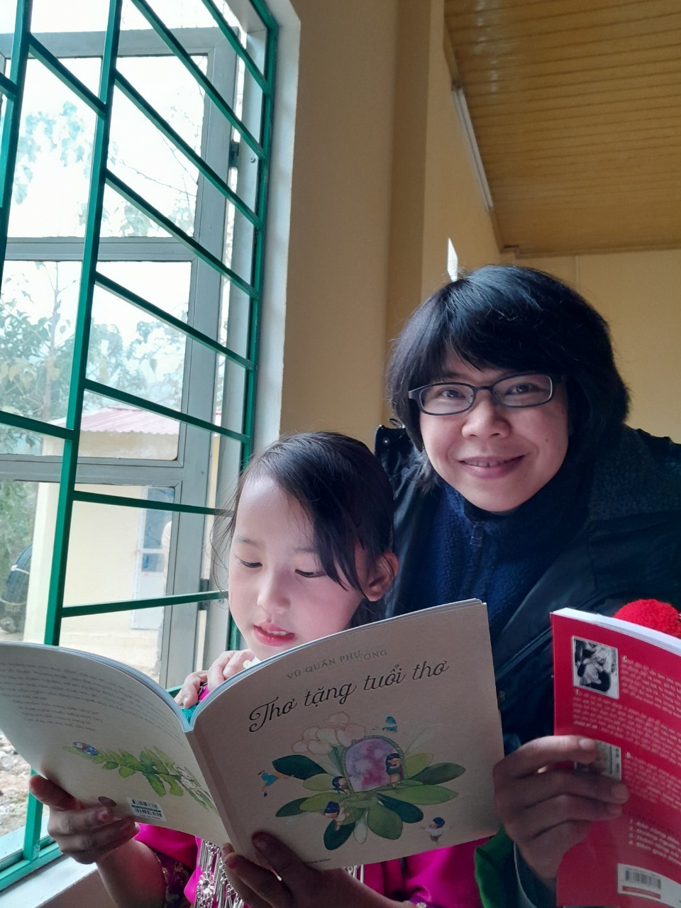 Các em hao hứng với những cuốn sách của NXB Kim Đồng. Điểm trường chưa có điện nên các em mang sách ra cửa sổ để đọc