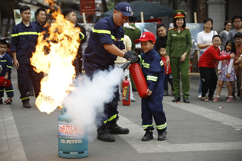 Các em học sinh được hướng dẫn sử dụng bình chữa cháy trong tình huống giả định