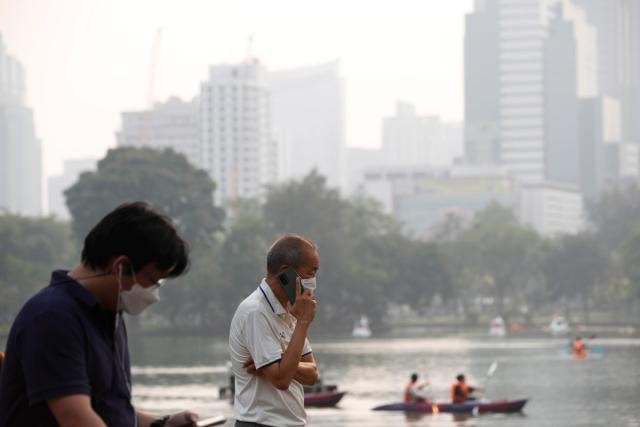 Ngừời dân đeo khẩu trang khi các tòa nhà cao tầng bị bao phủ bởi sương mù ở thủ đô Bangkok (Ảnh: EPA)