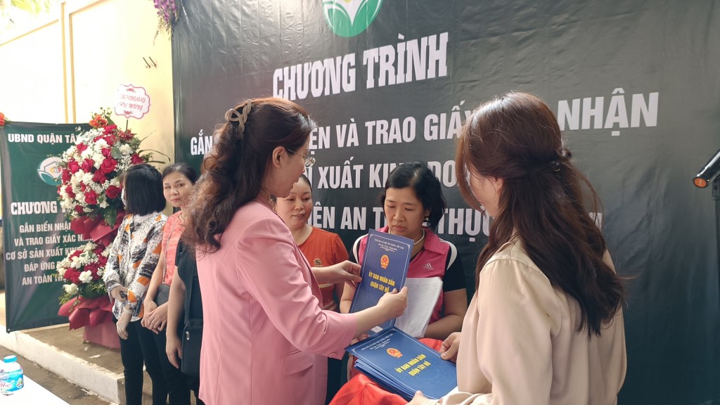 Bà Kiều Oanh trao giấy chứng nhận cho các hộ kinh doanh được gắn biển tại chợ Xuân La