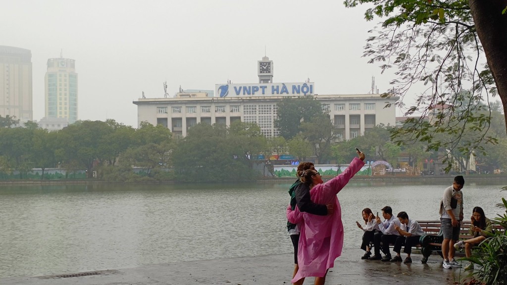 Đôi bạn người Pháp check-in bên bờ Hồ vào một chiều mưa tháng 4 Hà Nội. Theo hai người bạn nước ngoài này, đến Hà Nội có thể nhìn thấy những nét kiến trúc Pháp kiến cho việc trải nghiệm du lịch Thủ đô Hà Nội gần gũi, đem lại cảm giác an toàn, thân thuộc, 