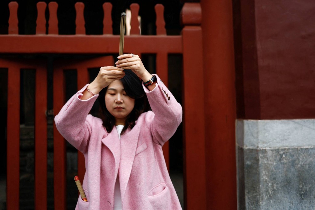 Một cô gái trẻ đến chùa cầu may mắn tại Chùa Lama, ở Bắc Kinh (Ảnh: Reuters)