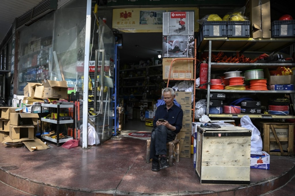 Người đàn ông cao tuổi ngồi trước cửa hiệu ở Như Đông ngày 27/4. Ảnh: AFP