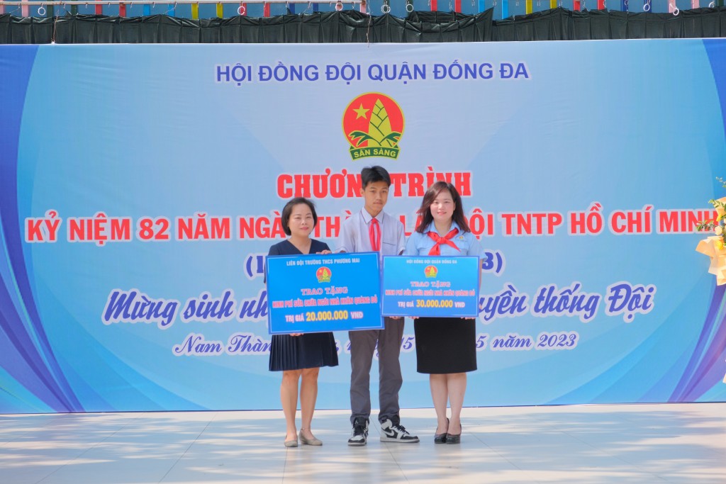 Đồng chí Nguyễn Thị Thanh Tâm – Bí thư Quận Đoàn, Chủ tịch Hội đồng Đội Quận và Cô Lê Thị Hồng Quế - Phó hiệu trưởng trường THCS Phương Mai lên trao tặng biển kinh phí tượng trưng sửa chữa Ngôi nhà khăn quàng đỏ cho gia đình em Trần Gia Kiệt