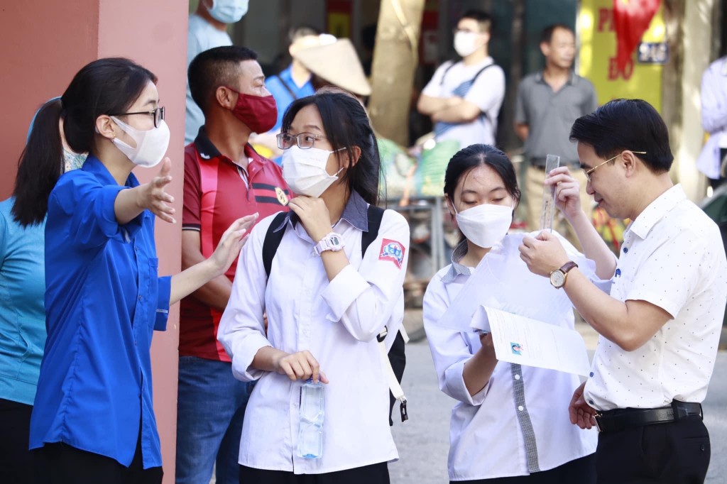  Nơi điểm thi tại trường THPT Cổ Loa, Đông Anh, một em học sinh đang nhận được sự hỗ trợ từ một bạn nữ thanh niên tình nguyên