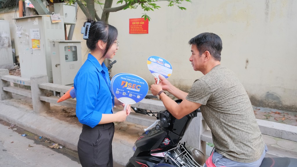 Tình nguyện viên tặng quạt cho phụ huynh chờ thí sinh phía ngoài cổng trường