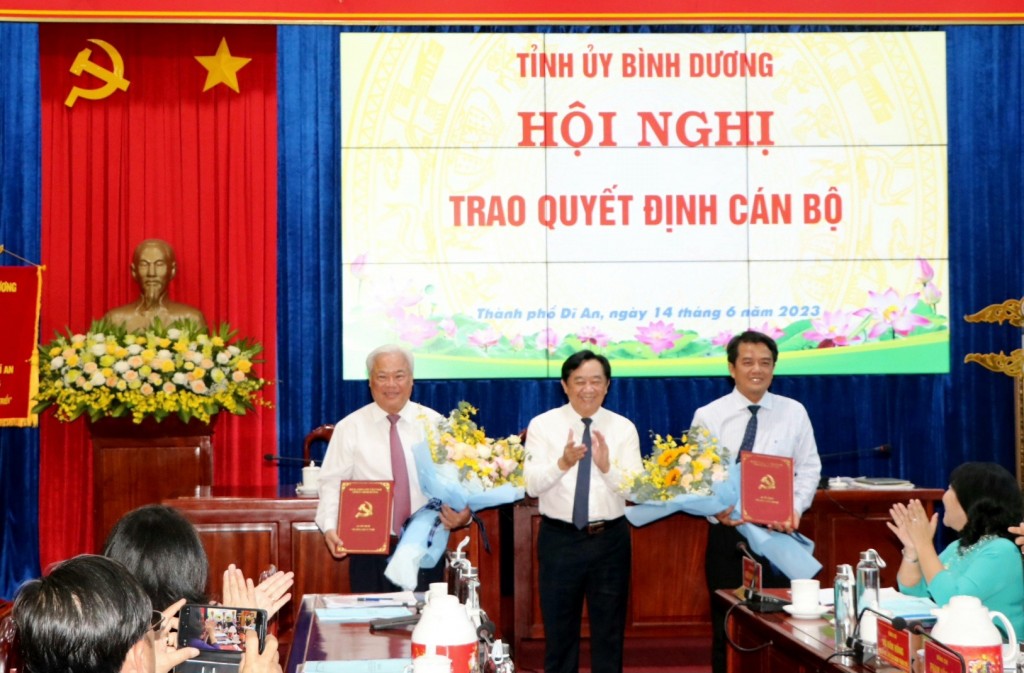 Ông Nguyễn Hoàng Thao, Phó Bí thư Thường trực Tỉnh ủy Bình Dương trao quyết định và tặng hoa chúc mừng ông Hồ Quang Điệp (bìa trái) và ông Bùi Thanh Nhân (bìa phải)
