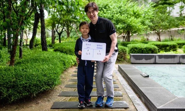 Yoon Jae-ha (trái), tạo dáng với tấm bảng trắng ghi tuổi quốc tế, 8 và tuổi Hàn Quốc, 9, bên cạnh cha anh, Yoon Dong-gun, ở Seoul (Ảnh: Getty Images