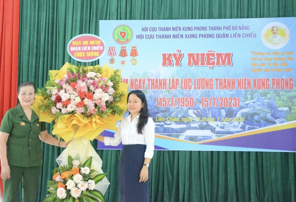 Chủ tịch Hội Cựu TNXP quận Liên Chiểu, Đinh Thị Phượng (trái) nhận hoa chúc mừng của Quận ủy - UBND - MTTQ quận