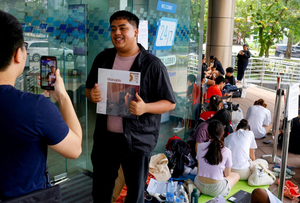 Một người hâm mộ tạo dáng với album vinyl của Taylor Swift khi anh ta chờ mua vé xem buổi hòa nhạc của Taylor Swift tại một bưu điện ở Singapore. Ảnh: Reuters