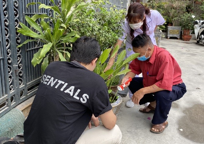 Cán bộ y tế, cộng tác viên hướng dẫn người dân tìm và diệt bọ gậy tại chậu cảnh có chứa nước.