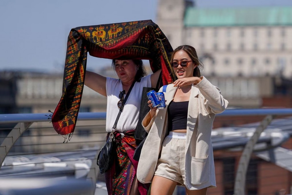 Người dân che nắng tại Cầu Thiên niên kỷ trong đợt nắng nóng ở London, Anh, ngày 18 tháng 7 năm 2022.
