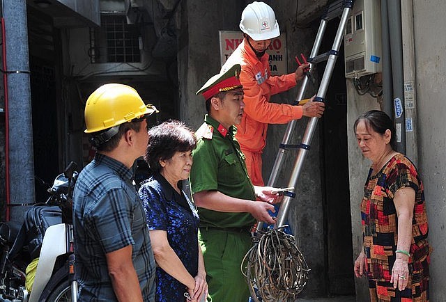 Cán bộ điện lực Hoàn Kiếm và công an phường Hàng Trống hướng dẫn người dân cách sử dụng các thiết bị điện, thiết bị PCCC