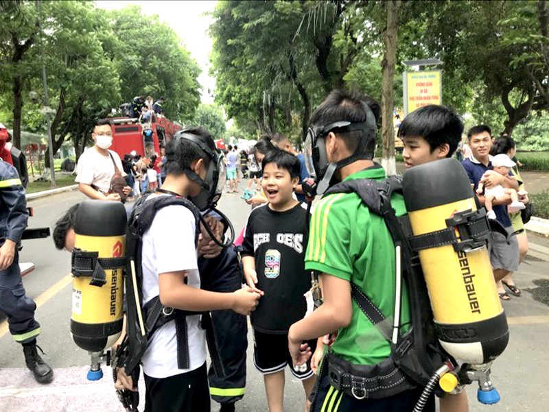 Cán bộ, chiến sỹ Đội Cảnh sát PCCC và CNCH Công an quận Long Biên hướng dẫn các em học sinh sử dụng mặt nạ, bình thở 