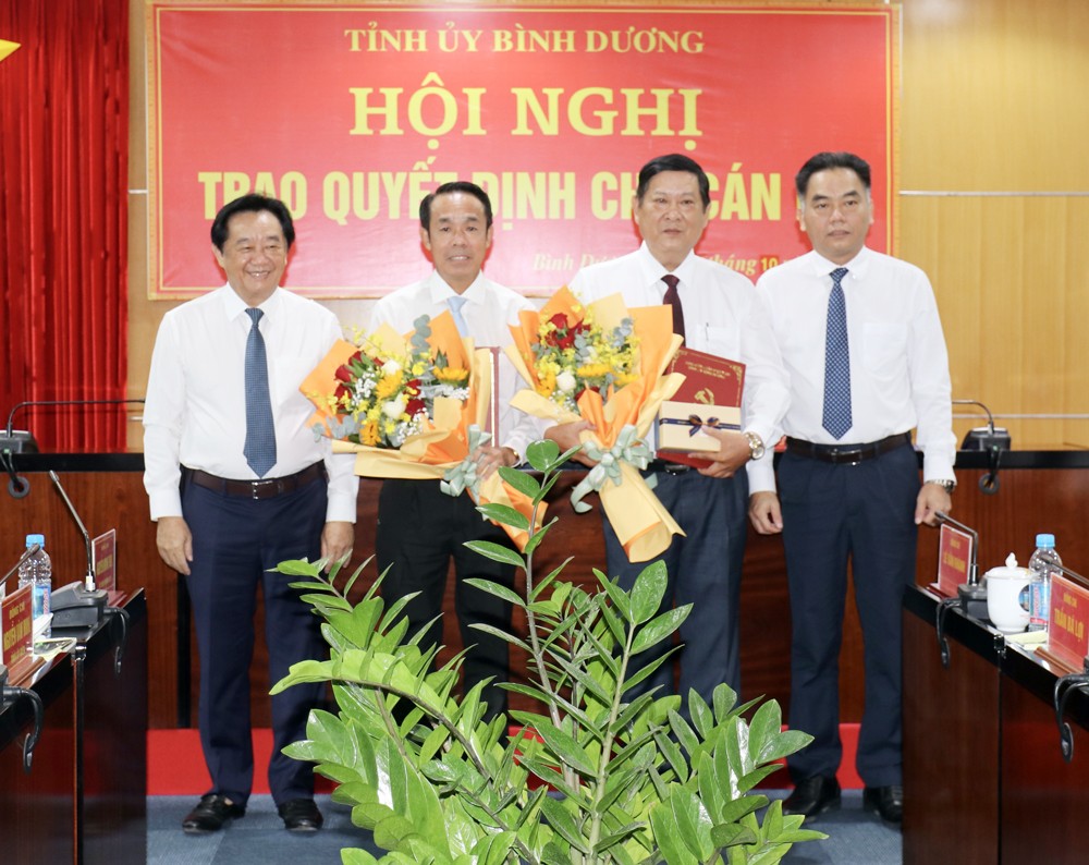 Lãnh đạo tỉnh Bình Dương trao quyết định và tặng hoa ông Trần Bá Lợi (thứ tư từ trái sang) và ông Lê Văn Khánh (thứ tư từ phải sang).