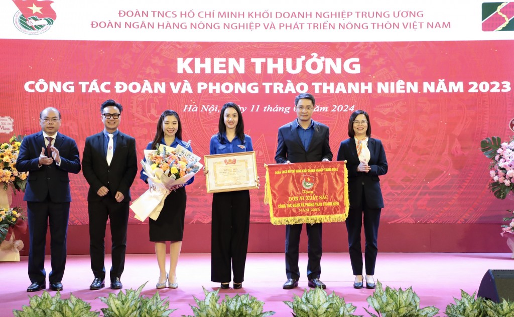 Đồng chí Hoàng Thị Minh Thu - Ủy viên Ban Chấp hành Đảng bộ Khối, Ủy viên Ban Thường vụ Trung ương Đoàn, Bí thư Đoàn Khối DNTW (ngoài cùng bên phải) và đồng chí Trần Văn Thịnh – Phó Bí thư Thường trực Đảng ủy Agribank (ngoài cùng bên trái) trao tặng Cờ thi đua của Ban Chấp hành Đoàn Khối DNTW cho Đoàn Thanh niên Agribank