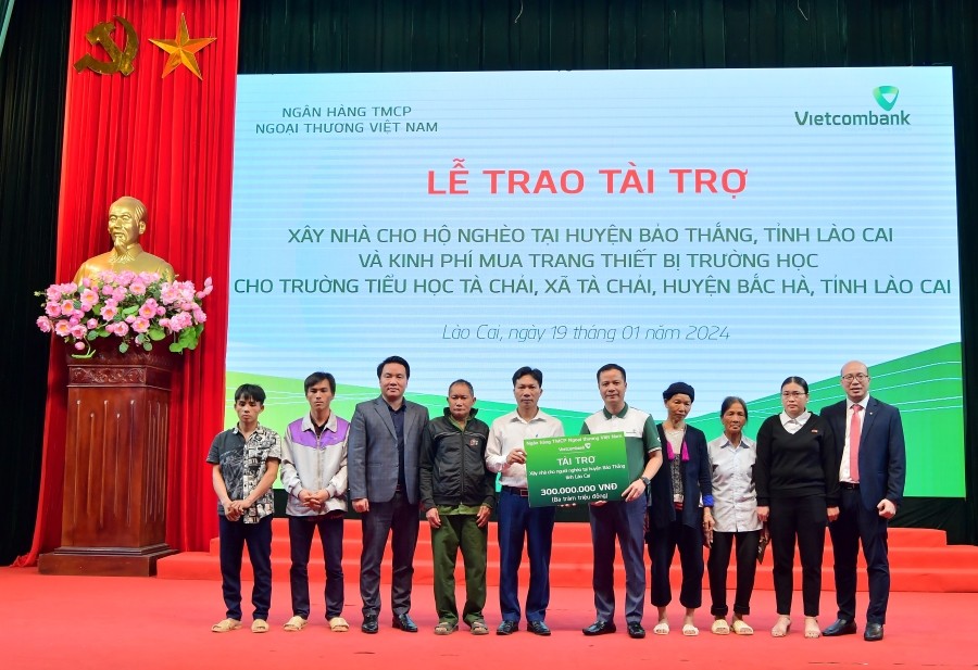 Ông Lê Hoàng Tùng - Phó Tổng Giám đốc Vietcombank (thứ 5 từ phải sang) cùng ông Đặng Việt Hùng - Giám đốc Vietcombank Lào Cai (ngoài cùng bên phải) trao biểu trưng hỗ trợ kinh phí xây dựng nhà cho 6 hộ gia đình khó khăn tại huyện Bảo Thắng, tỉnh Lào Cai