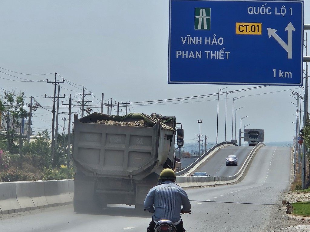 Đoàn xe chở vật liệu phục vụ dự án, chạy qua đường dẫn vào cao tốc Phan Thiết – Dầu Giây làm rơi vãi đá vật liệu xây dựng xuống mặt đường (Ảnh H.Quảng)