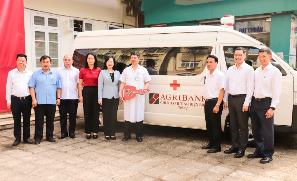 Các đồng chí đại biểu chụp ảnh lưu niệm bên chiếc xe cứu thương trao tặng cho Bệnh viện Đa khoa tỉnh Điện Biên