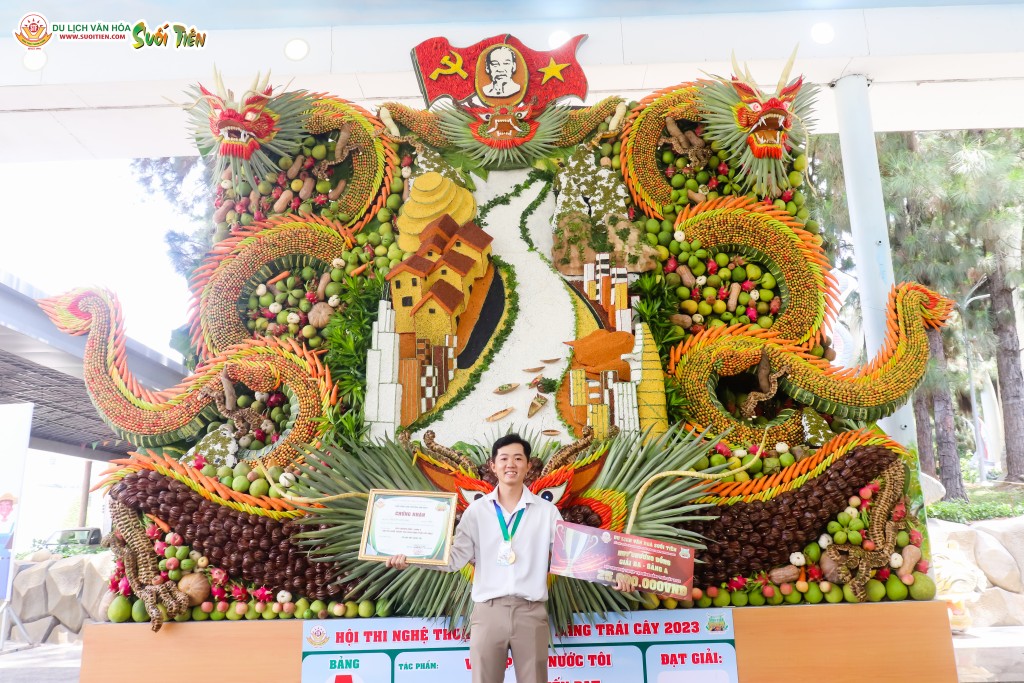Nghệ nhân Nguyễn Tiến Đạt chụp hình kỷ niệm cùng tác phẩm của mình trong Hội thi Nghệ thuật tạo hình bằng trái cây 2023