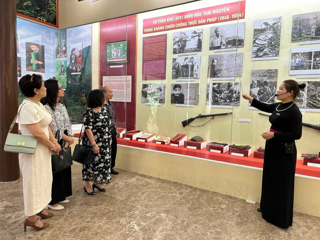 Chị Hiền giới thiệu cho các đại biểu đoàn Hội Nhà báo Hà Nội về ảnh tư liệu và hiện vật trong Bảo tàng tại ATK