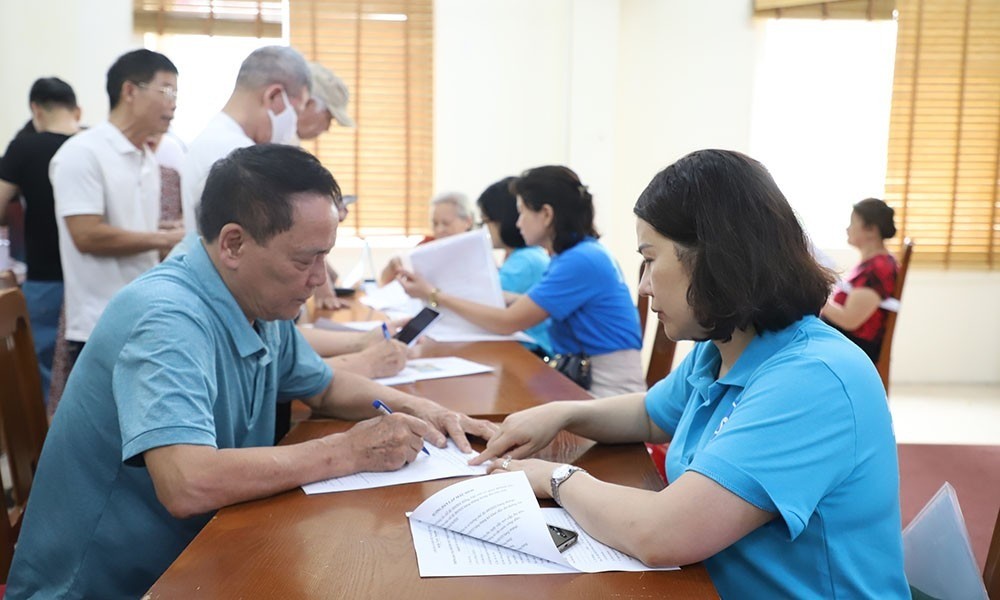 cán bộ BHXH quận Thanh Xuân hỗ trợ về thủ tục mở tài khoản nhận lương hưu hằng tháng. Ảnh: Hà Hùng.