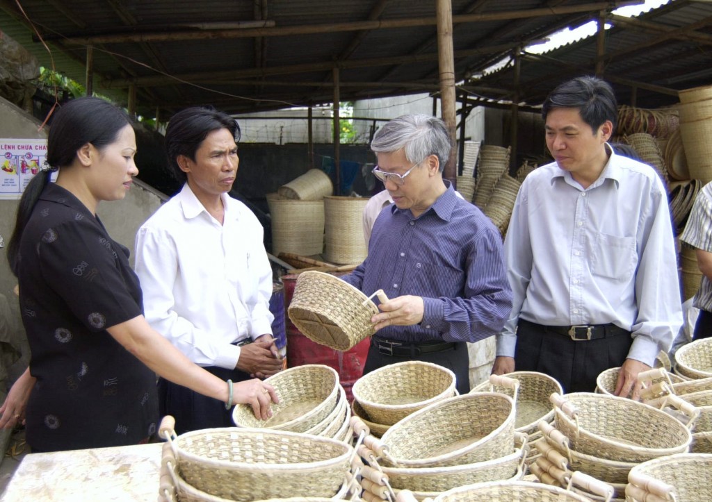 Bí thư Thành ủy Hà Nội Nguyễn Phú Trọng xem sản phẩm thủ công tại huyện Thanh Trì, tháng 9-2000. Ảnh: HNM