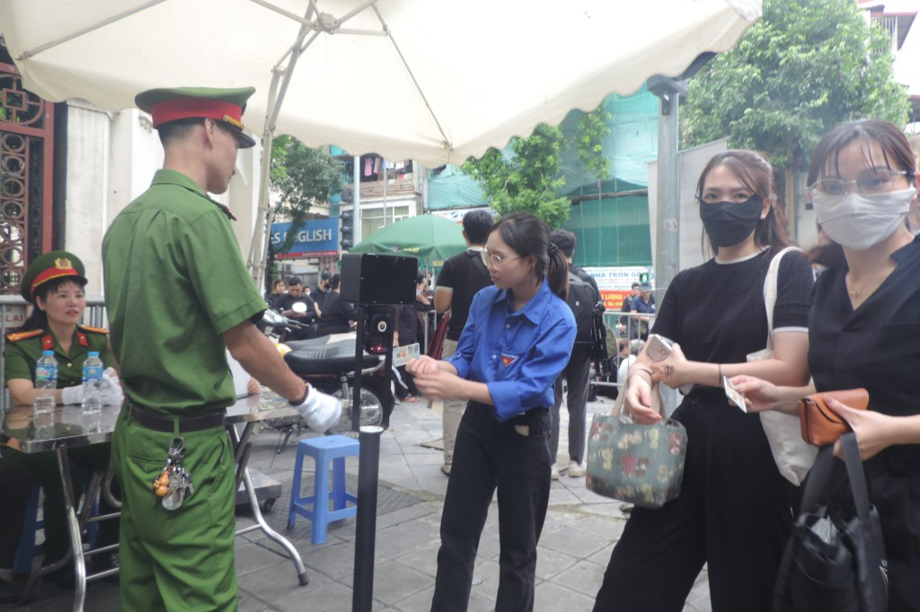 Tình nguyện viên hỗ trợ người dân quét mã để vào lễ viếng 
