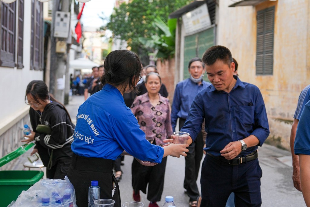 Tình nguyện viên phát nước cho người đến viếng Tổng Bí thư