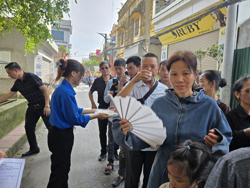 Những chiếc quạt giấy cũng được các bạn trẻ xã Đông Hội phát miễn phí cho người dân trong lúc chờ đợi