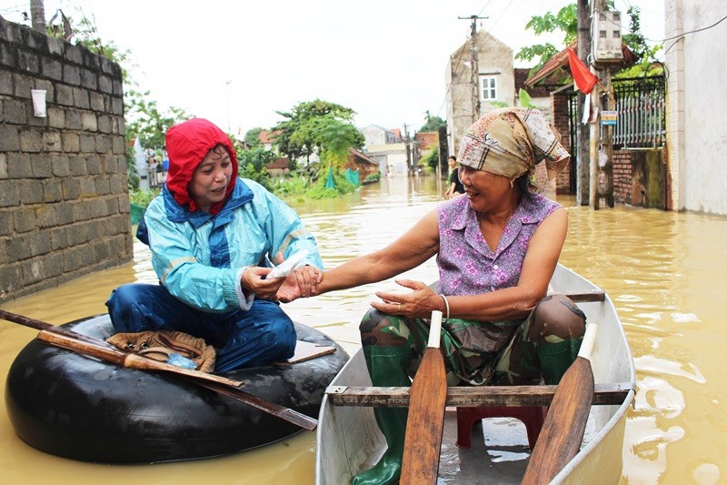 Cán bộ Trung tâm Y tế huyện Chương Mỹ cấp thuốc, hướng dẫn người dân chăm sóc sức khỏe trong những ngày ngập lụt. Ảnh Bảo Châu