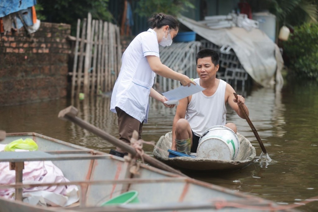 Nhân viên y tế xã Cấn Hữu tuyên truyền, phát thuốc cho người dân xóm Bến Vôi chủ động phòng, chống dịch bệnh sau mưa ngập. Ảnh: Minh Quyết/TTXVN