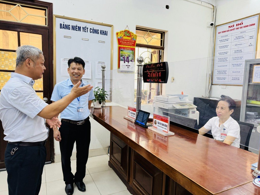 Đồng chí Bùi Minh Hoàng - Trưởng phòng Xây dựng nếp sống văn hóa và Gia đình (Sở Văn hóa và Thể thao Hà Nội) trao đổi với cán bộ một cửa phường Sơn Lộc (thị xã Sơn Tây)