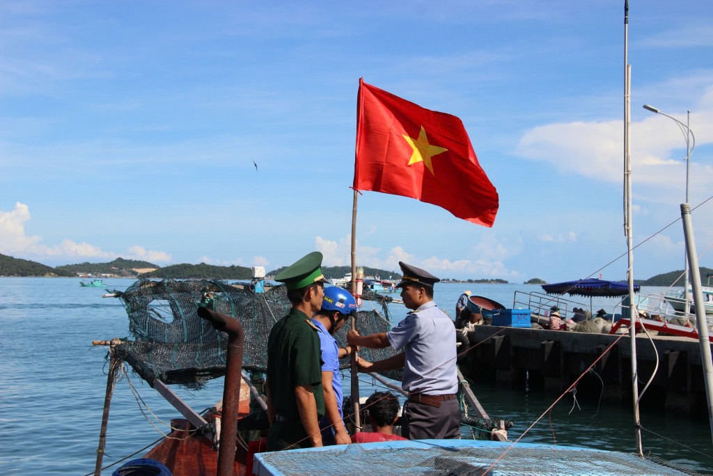 Lá cờ đỏ sao vàng tung bay trước mũi những đoàn tàu của ngư dân bám biển (Ảnh H.Quảng)