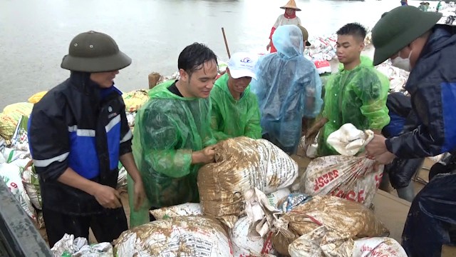 Người dân sử dụng bao tải để đắp đất nhằm ngăn nước từ sông Tích tràn vào