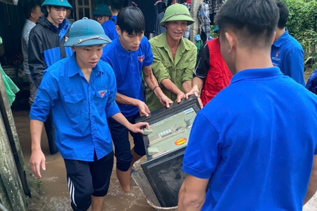 Thanh niên hỗ trợ người dân vùng bị ngập lụt di chuyển đồ đạc 