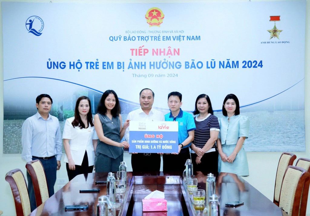 Ông Đinh Tiến Hải - Giám đốc Quỹ BTTEVN nhận biển tài trợ từ đại diện Nestle Việt Nam trao hỗ trợ trẻ em và gia đình bị ảnh hưởng bão lũ