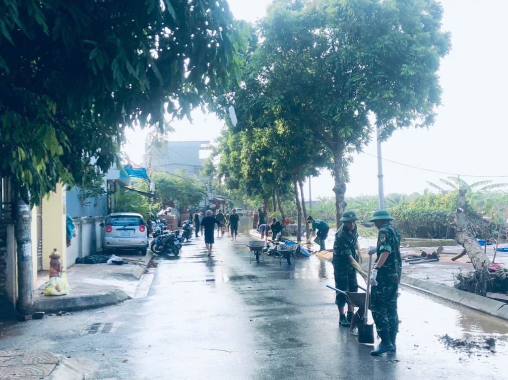 Thanh niên Long Biên hỗ trợ người dân vệ sinh, rửa bùn trên đường sau khi nước rút