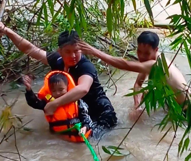 Đồng chí Đại uý Lục Văn Nguyên (áo đen) và anh Liệu Văn Quyết đưa cháu Bảo vào bờ an toàn (Ảnh: Cổng TT ĐT Bộ Công An)