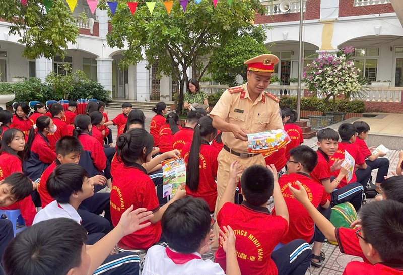 Cán bộ Đội Cảnh sát GTTT phát tờ rơi tuyên truyền ATGT cho các em học sinh tại trường THCS Minh Khai, Bắc Từ Liêm, HN