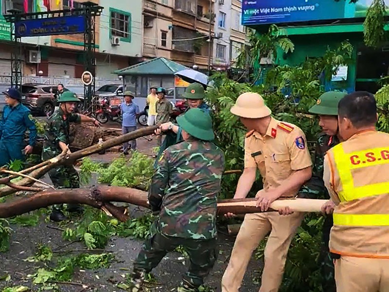 Lực lượng CSGT phối hợp với các lực lượng chức năng thu dọn cây đổ tại các tuyến phố ngay sau khi gió bão vừa tan