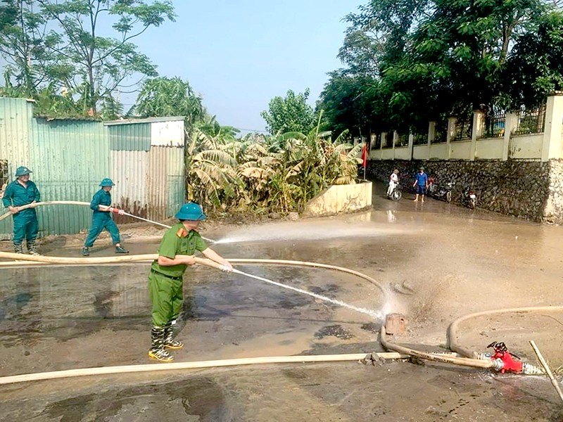 Lực lượng Công an phối hợp dân quân tự vệ, các đoàn thể xã Trung Châu, huyện Đan Phượng sử dụng máy bơm công suất lớn xịt rửa bùn đất đọng lại trên các tuyến đường sau khi nước lũ rút.