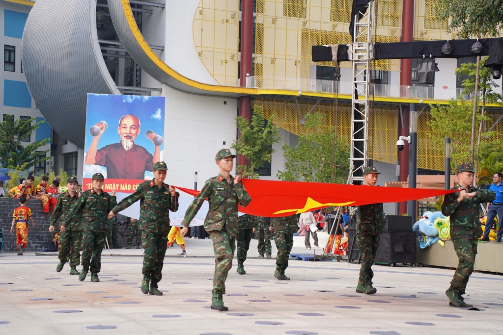 Đi đầu là hình ảnh Cờ đỏ sao vàng - Hồn thiêng Tổ quốc với nền đỏ tượng trưng cho màu của cách mạng, màu của sự hi sinh, vinh quang ông cha ta ngã xuống vì nền độc lập dân tộc, tự do của Tổ quốc và hạnh phúc của Nhân dân.