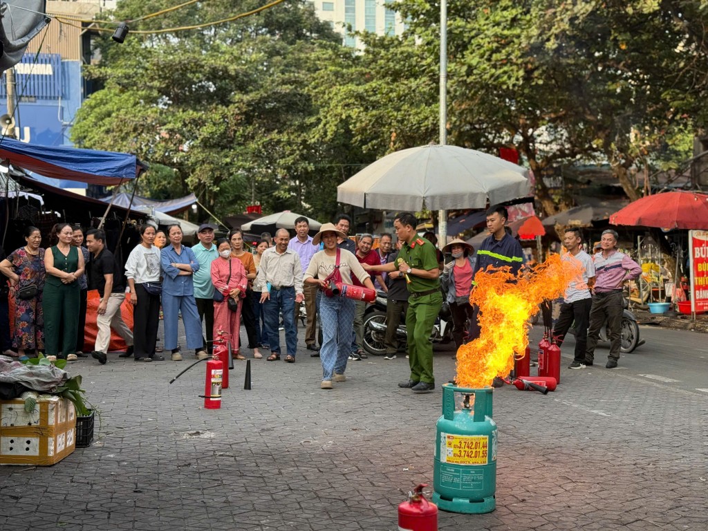 Cán bộ Cảnh sát PCCC và CNCH Công an quận hướng dẫn bà con cách dùng bình xịt khí